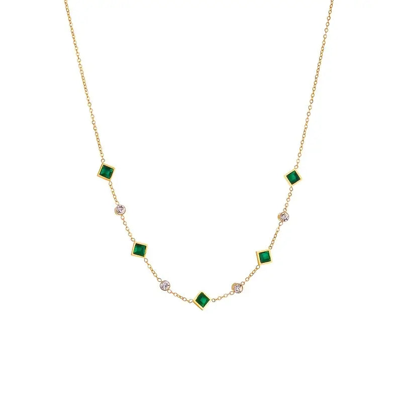Colar geométrico dourado com esmeraldas, estilo estação, da marca Rose & Oliver, com pingentes de formas modernas.