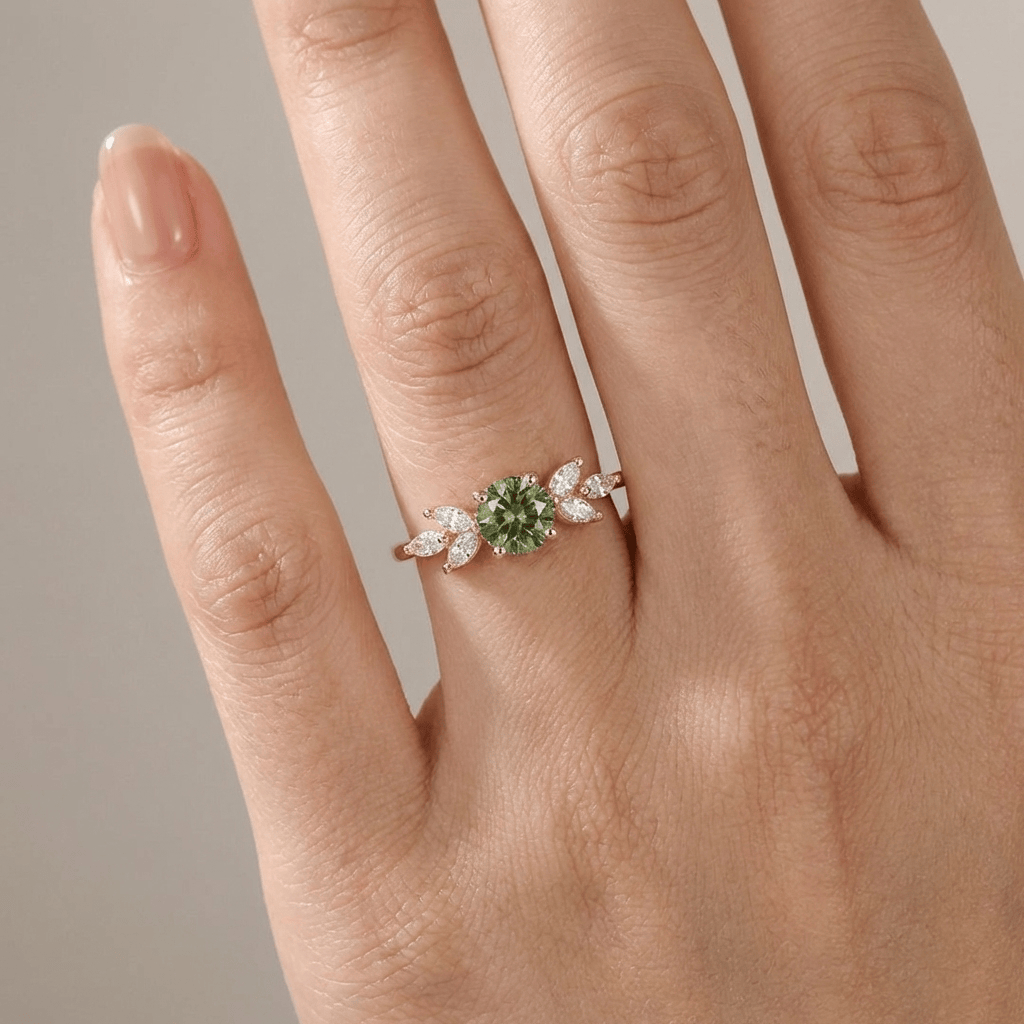 Anel delicado de ouro com peridoto verde em formato de folha, da marca Rose & Oliver, exibido em fundo neutro.