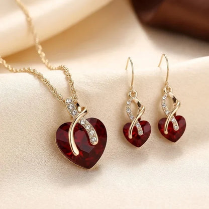 Conjunto de joias Rose & Oliver com coração torcido dourado e rubis vermelhos, incluindo colar e brincos elegantes para ocasiões especiais.