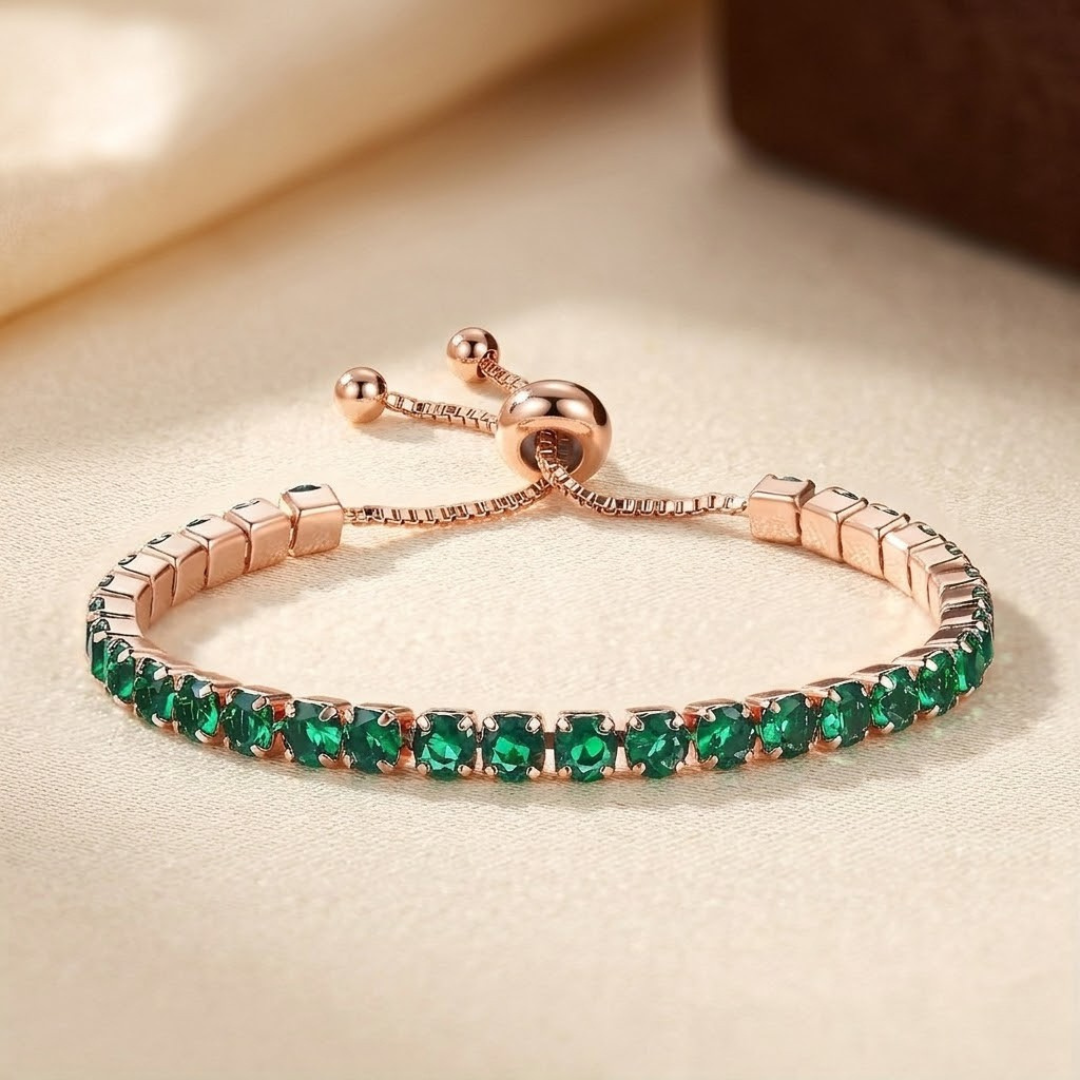 Pulseira ajustável de tênis com ouro e esmeraldas, marca Rose & Oliver, exibindo detalhes elegantes e pedras verdes brilhantes.