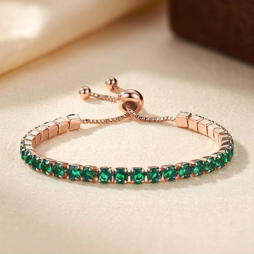 Pulseira ajustável de tênis com ouro e esmeraldas, marca Rose & Oliver, exibindo detalhes elegantes e pedras verdes brilhantes.