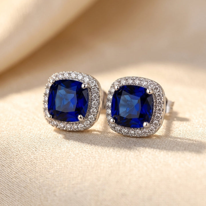 Brincos de prata com safira em halo, estilo stud, da marca Rose & Oliver, com design elegante e brilhante.
