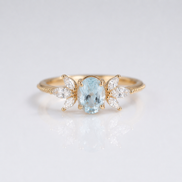 Anel dourado com pedra aquamarina marquise, da marca Rose & Oliver, exibindo detalhes elegantes e brilho sofisticado.