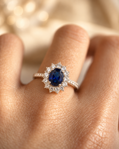 Anel de ouro com halo de safira azul e detalhes brilhantes, da marca Rose & Oliver, mostrando o design elegante e sofisticado.